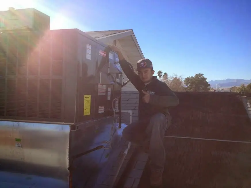 HVAC technician performing Heat Pump Repair on a rooftop unit in Greenfield
